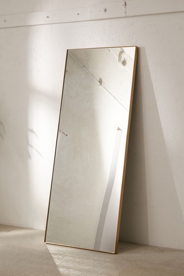 rectangular floor mirror leaned against wall with polished brass frame