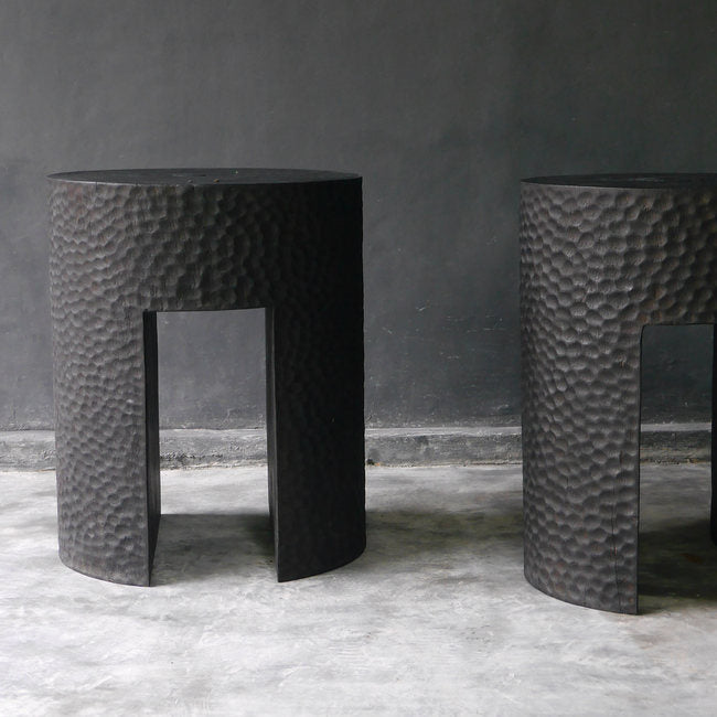 two black textured stools, one fully visible and the other partially out of frame