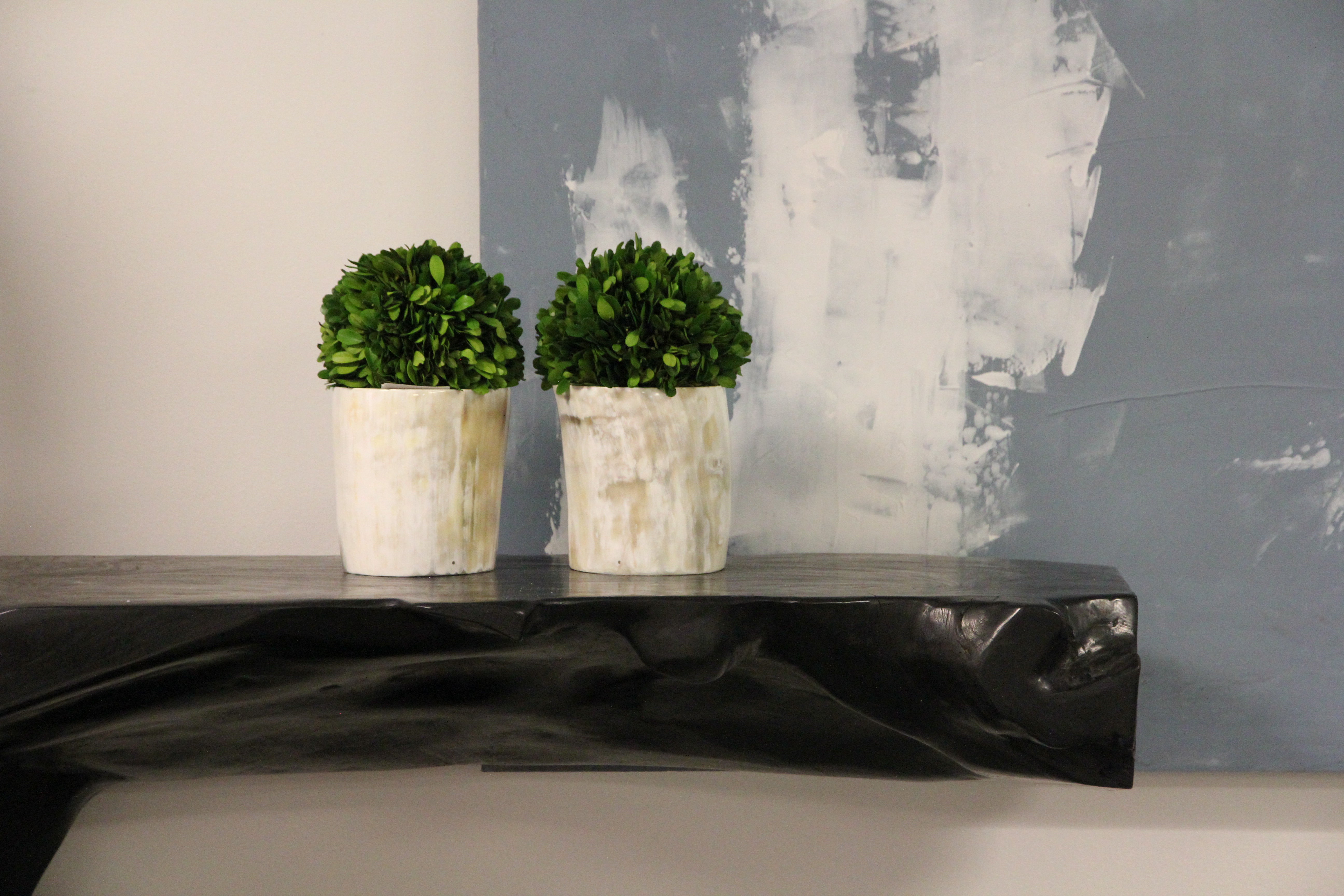 two of the vases with plants inside on top of console table