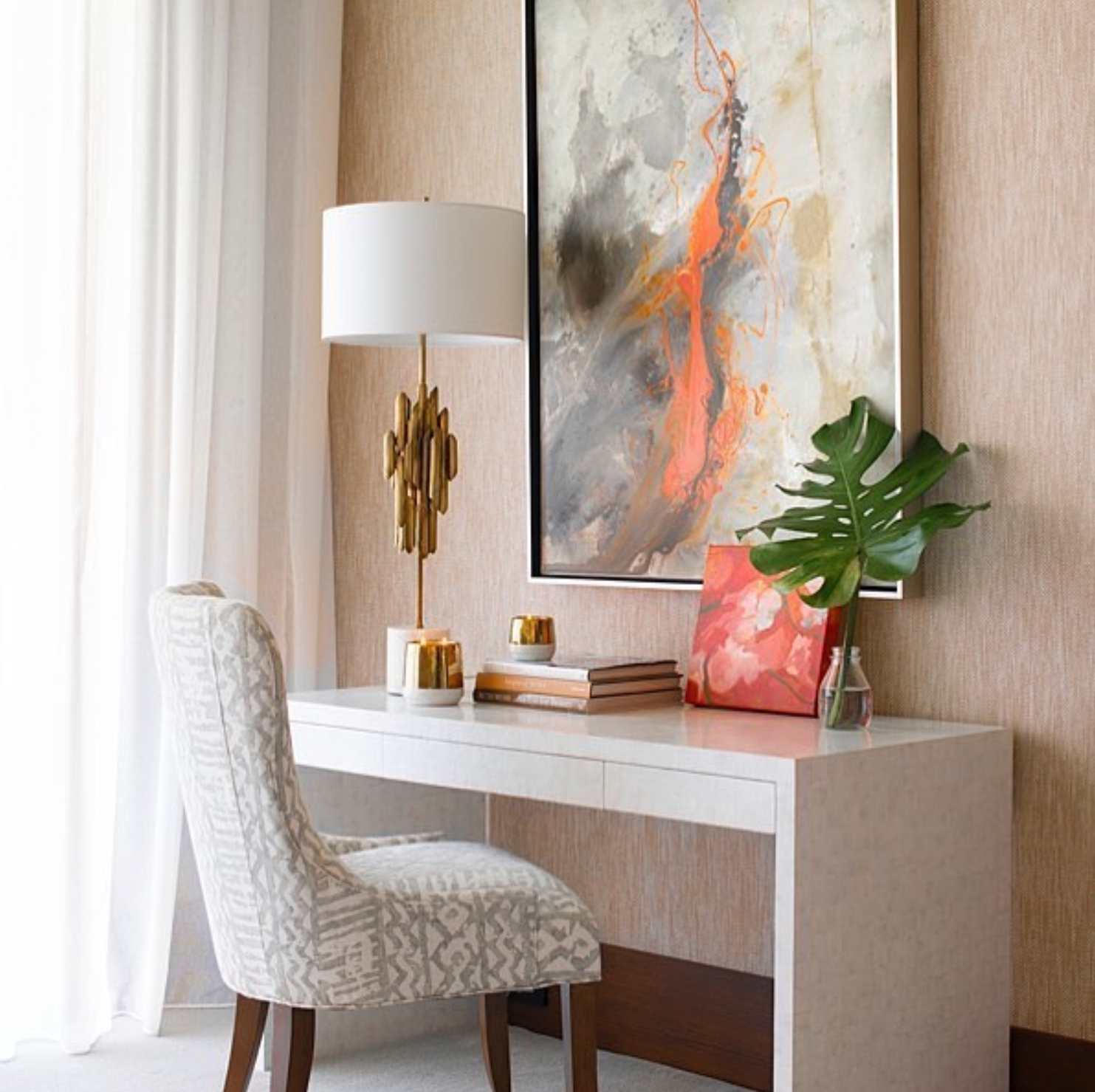 white shell desk styled below wall art with accent chair and decor